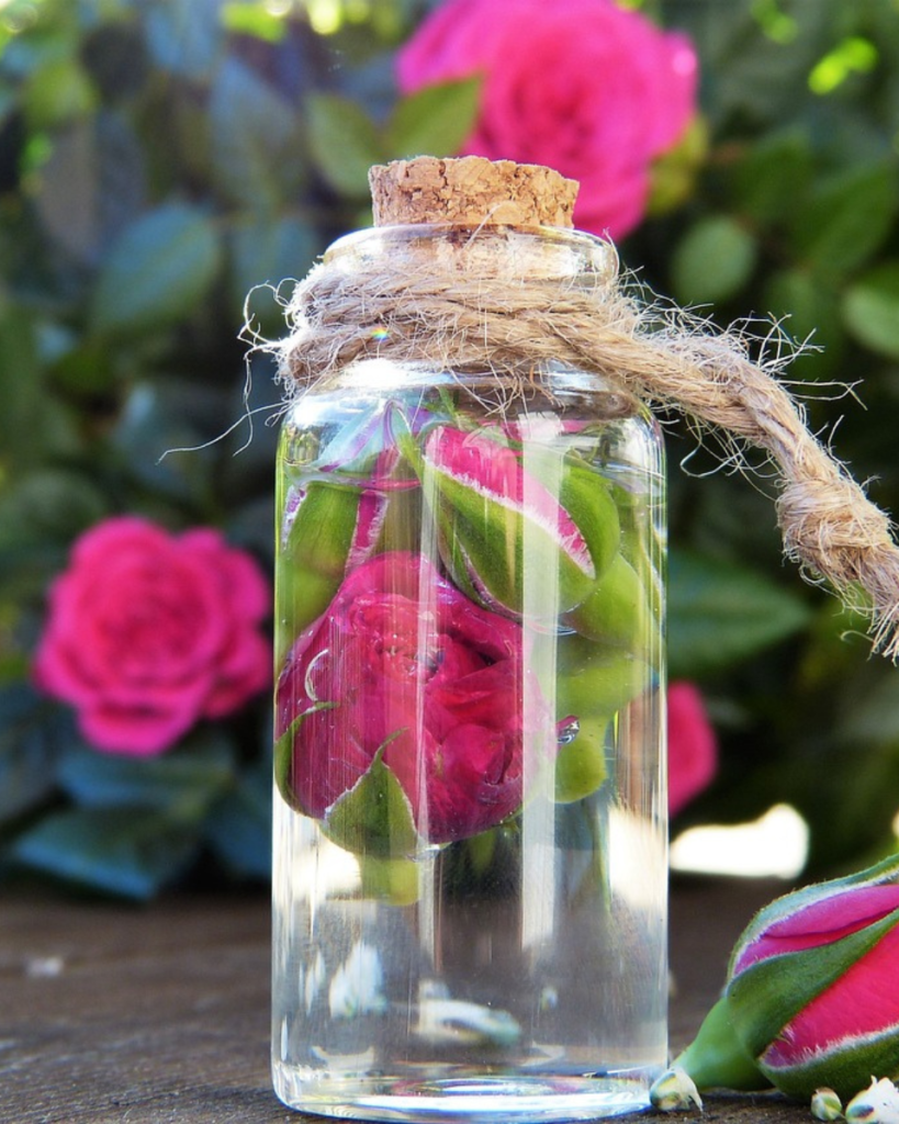 rose water in a glass bottle with a rose inside