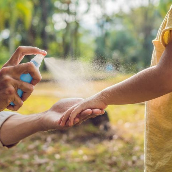 A man spraying diluted lemongrass oil on his child